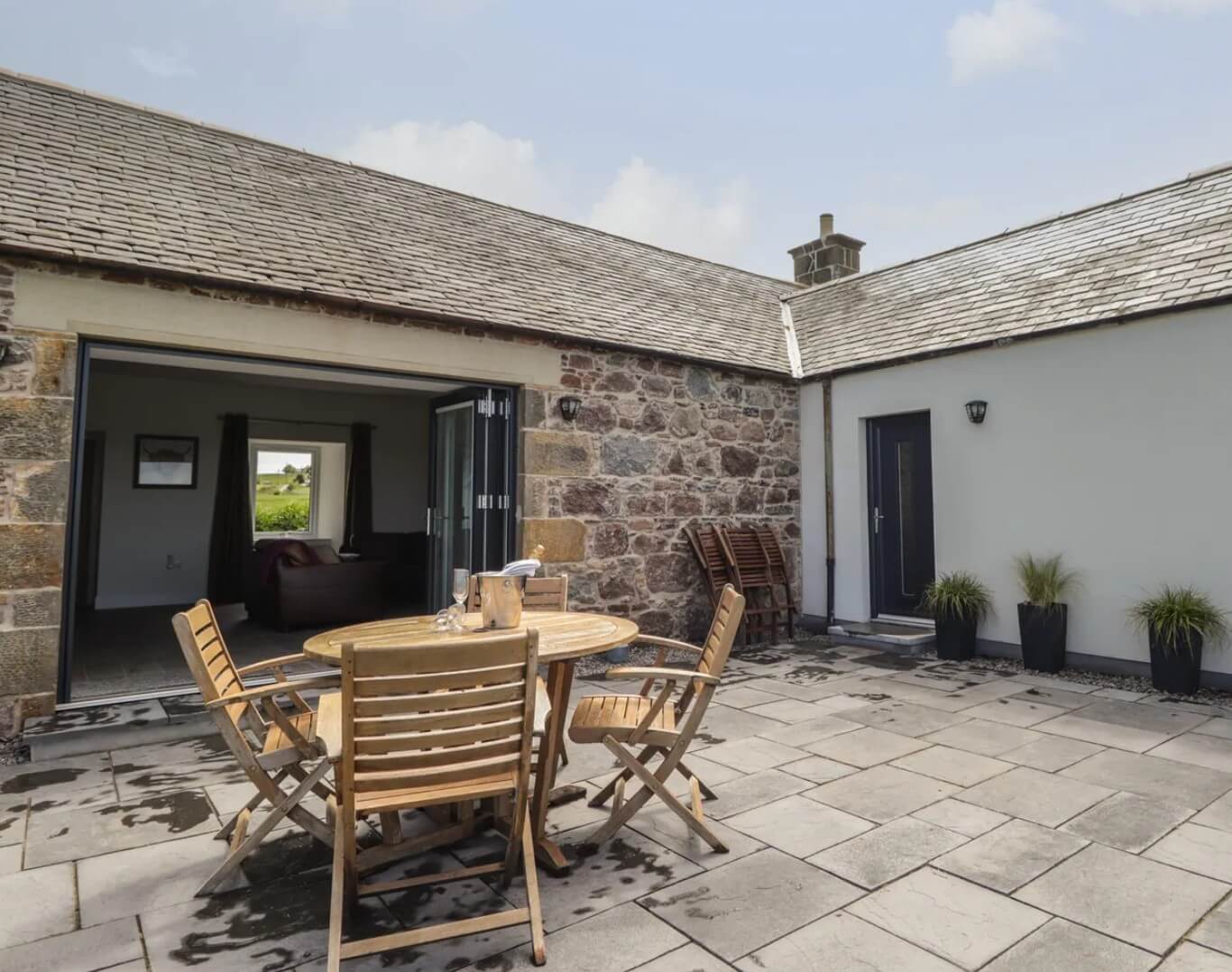 A cosy cottage interior featuring a warm, lit wood-burning stove with soft armchairs in Nairn.